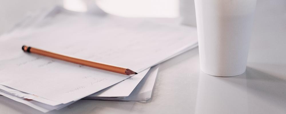 notepad, pen, and coffee mug on a table